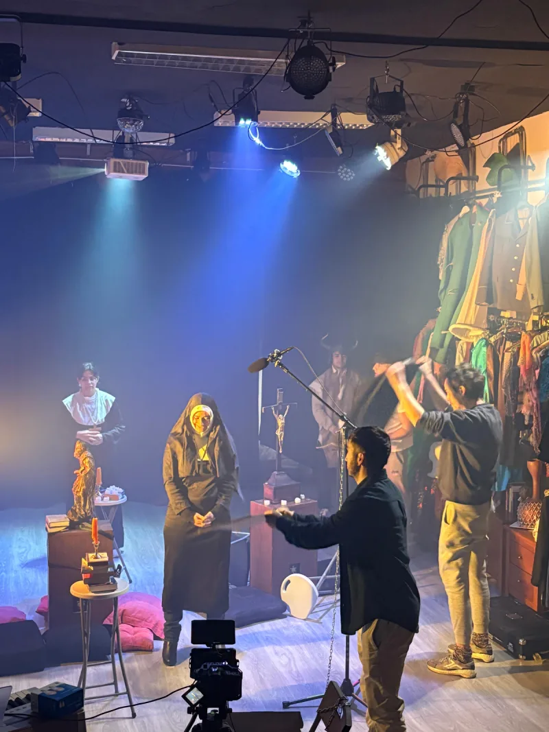 Equipo técnico y actores trabajando durante el rodaje de una escena de época con dirección, sonido, iluminación y puesta en escena profesional.