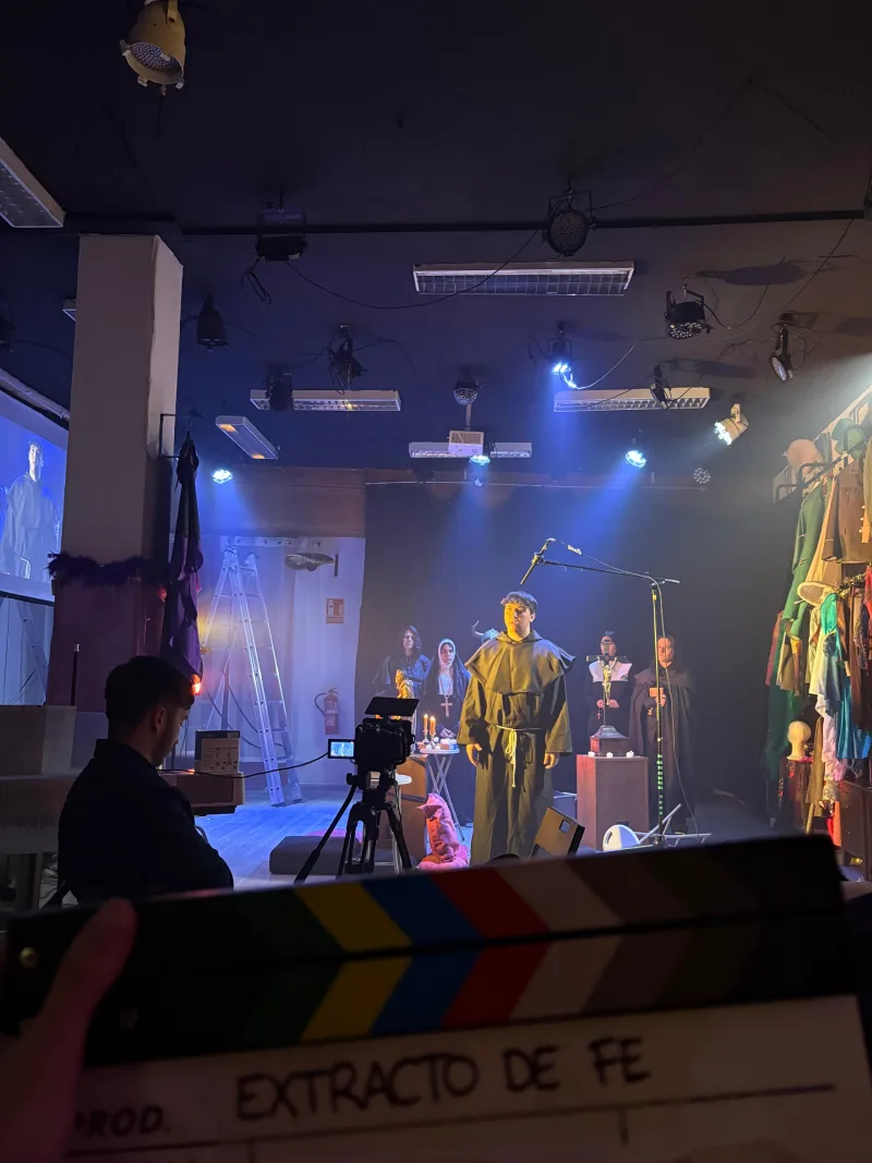 Rodaje real de una escena de época con iluminación cinematográfica, vestuario, utilería y equipo técnico profesional.